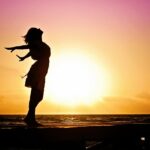 Frau vor untergehender Sonne
